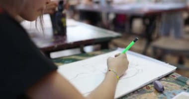 A child in the classroom draws with a pencil, side view. Development of creative abilities, teaching fine arts