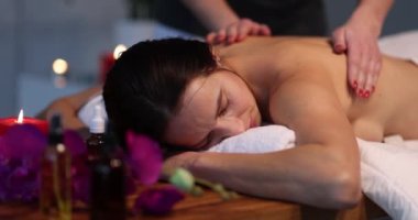 The masseur strokes the back of a lying woman, slow motion. Thai relaxing body massage in the salon