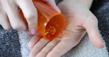 Female hands with corns pour jelly capsules from a jar, close-up. Lack of vitamins in the body, dietary supplement