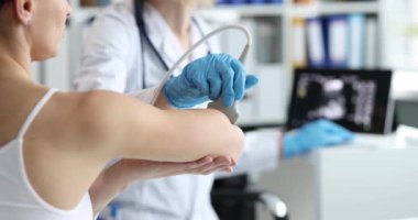 The doctor in the process of ultrasound of the hand, close-up, slow motion. Diagnostics of the elbow joint, examination