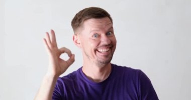 Cheerful young man shows ok with gestures, close-up. An expression of joy and success. Emotional male character