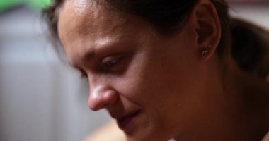 Upset woman looks down and cries, face close-up. Depression and loss, stress and trouble, loneliness