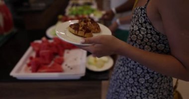 Woman hand holds plate with delicious fresh buns and cakes. Sweet dessert selection for dinner