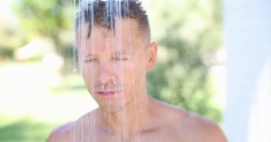 Young handsome man takes summer shower outdoor.