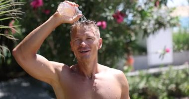 Handsome man douses himself with cold water from bottle in summer. Sultry heat in summer and cool shower concept