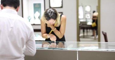 Woman looks at shop window and chooses piece of jewelry. Jewelry and products in store