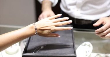 Jewelry store and young woman trying on expensive bracelet closeup. Choosing beautiful expensive bracelet on hand concept
