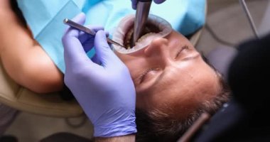 Dentist examines and treats patient teeth at dentist and dental instrument. Doctor examines oral cavity of patient in dental clinic