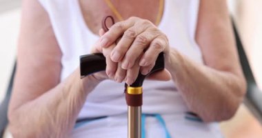 Hands of elderly woman with wooden cane. Old age loneliness and medical care