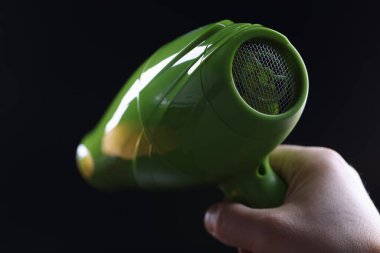 Person holds hair dryer back view and shows metal mesh covering inside of device. Overheating of hair dryer and high-quality safe hair drying