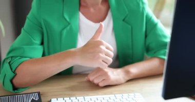Businesswoman gesturing thumbs up in monitor screen at workplace. Remote recommendations for excellent work and likes for effective work