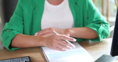 Businesswoman boss is studying financial performance data in chart and crosses arms over chest. Confident marketer manager at workplace working with analytics and statistics documents