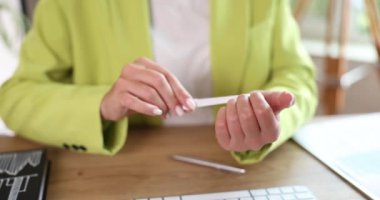 Businesswoman at workplace sawing nails with nail file. Girl makes manicure in the workplace