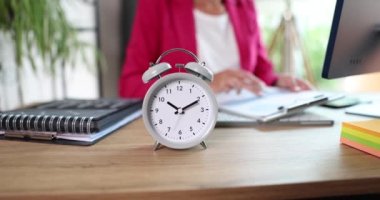 Business woman studying documents with data on table with alarm clock. Analysis of financial indicators and planning for sales growth