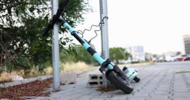 E-scooter tied to a pole on the street, slow motion. Mobile urban transport, active leisure, scooter lock