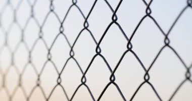 Fencing from a galvanized chain-link mesh on a gray background, close-up. Mesh fencing steel wire