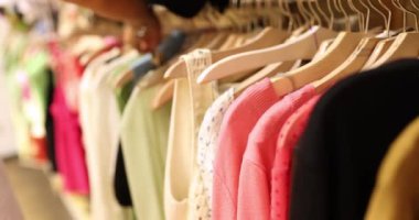 Many bright womens things hang on hangers, close-up, shallow focus. Second hand shop, clothes warehouse