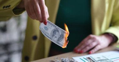 Ofisteki bir kadın 100 dolar yakıyor, yakın plan. Kara para aklama, kanıt yok etme kavramı.