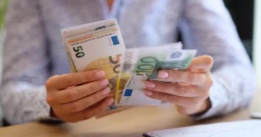 Ofisteki bir kadın para sayıyor, avroya yakın çekim, yüzeysel odaklanma. Avrupa para biriminde maaş, değer kaybı