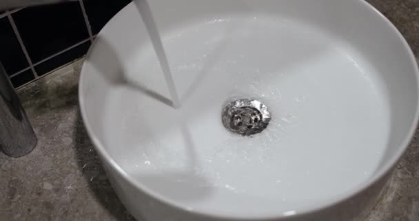 一股来自铬水龙头的水倒入了一个白色的水池 这是特写 现代浴室装置 — 图库视频影像