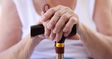 Yaşlı eller bastona yaslanır, yakın plan, yüzeysel odaklanma. Yaşlılarla ilgilenmek, huzurevi...