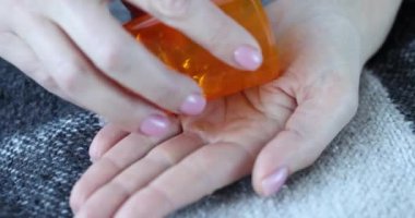 Dişi eller, yakın plan portakal kapsüllerini palmiyeye döker. Besleyici maddeler, diyet, vücut desteği