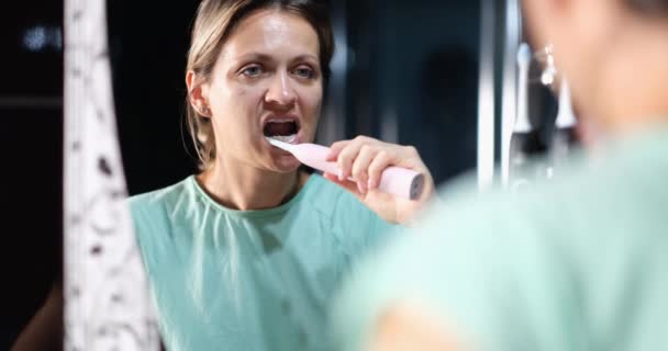 Ung Kvinna Framför Spegel Borstar Tänderna Med Elektrisk Borste Närbild — Stockvideo