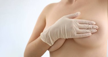 Elleri lastik eldivenlerle kaplı kadın göğüsleri. Mammoplasti ve estetik cerrahi ve kozmetik kliniği konsepti