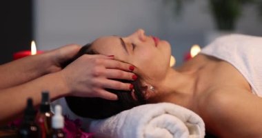 Kadın masör, beyaz kadınlara geleneksel kafa ve yüz masajı yapar. Spa merkezinde uzanan kadın rahatlatıcı masaj yapıyor.