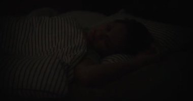 Kadın parlak mavi ışığı yanıp sönen odada huzur içinde uyuyor. Sakin uyku konsepti