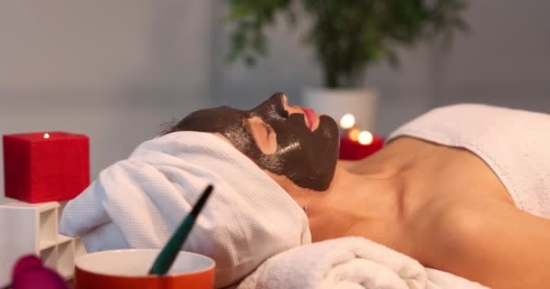 在漂亮女人的脸上涂黑色面罩的程序 美容院温泉疗养及面部皮肤护理 — 图库视频影像