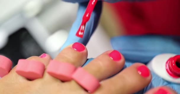 ペディキュアマスターはネイルサロンの女性の爪に赤ピンクのポリッシュを適用します 美しい絵のコンセプト — ストック動画