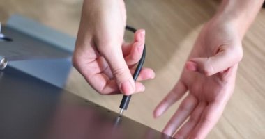 Kadın eli siyah USB-C ya da C tipi güç kablosunu bağlıyor. Laptop bilgisayarının USB-C portuna siyah flaş bellek kablosu