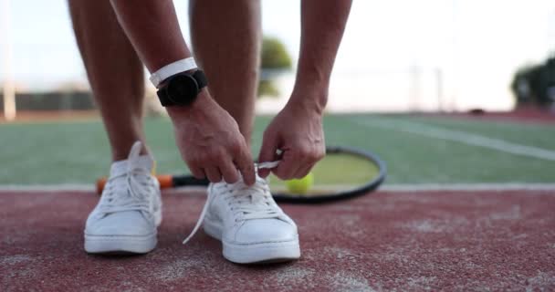 テニスコートの白いテニスシューズに靴ひもを結ぶ男 テニスのための質の高いスポーツシューズ — ストック動画