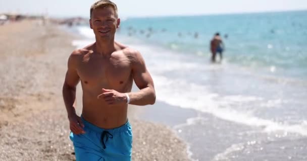 微笑的英俊男子在海滩上沿着大海奔跑 暑期慢跑与健康 — 图库视频影像