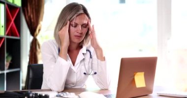 Masada oturan yorgun kadın doktor, elinde filmle şakağa masaj yapıyor. Tıbbi personel kavramının duygusal çöküntüsü