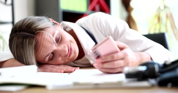 Müde Ärztin Liegt Auf Dem Tisch Und Schaut Ins Telefon — Stockvideo