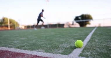 Sarı top yeşil kort yüzeyinde yatıyor, yakın çekim, yavaş çekim. Tenis oynama, antrenman yapma kavramı