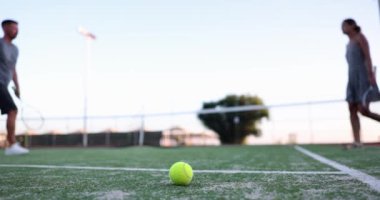 Sarı top saha yüzeyinde yatıyor, oyuncular el sıkışıyor, yavaş çekim. Tenis oyununu bitiriyorum.