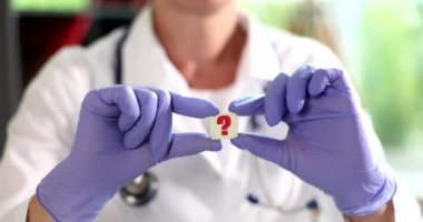 Üzerinde soru işareti olan bir rozet tutan kadın doktor. Tıbbi sorular ve cevaplar konsepti