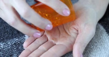 Altın kapsüller kavanozdan ele dökülür. Omega 3 ve yağ asitleri konseptinin faydaları