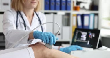 Doktor, klinikte bacakları yakından gören ultrason cihazıyla diz eklemlerini ultrasona sokuyor. Diz eklemlerinin ultrasonu