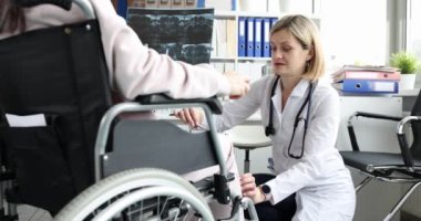 Kadın ortopedik doktor, klinikte tekerlekli sandalyedeki kadının dizine çekiçle vurdu. Omurga yaralanmaları ve rehabilitasyon