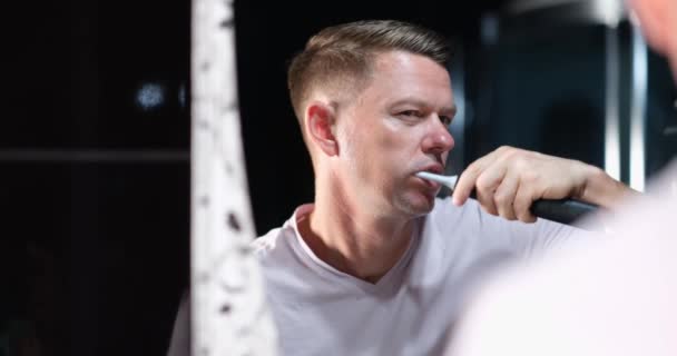 Bonito Homem Escovando Dentes Com Irrigador Oral Elétrico Olhando Espelho — Vídeo de Stock