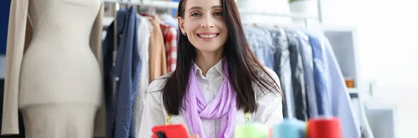 職場でスマホを持っている笑顔の女性 プロのファッションスタイリストのコンセプト — ストック写真