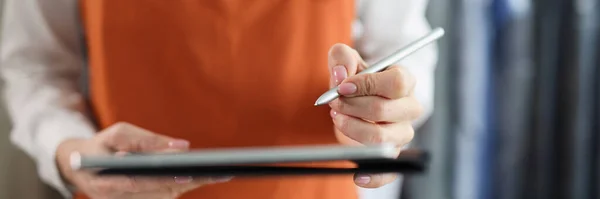 Tablet with stylus in female hands in uniform. Receiving and issuing order concept