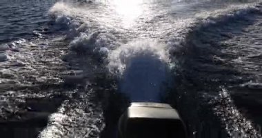 Sürat teknesinin dikiz aynasından gelen dalgalar. Dalgalardan beyaz köpük ve okyanusta yüzen tekne.