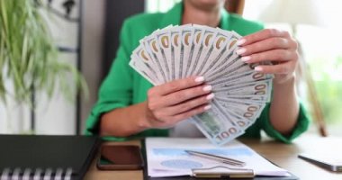 İş kadını çalışanın elinde dolar banknotları içinde nakit para fanı var. Başarı kariyer kavramı ve finansal gelir