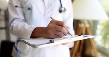 Doktor klinikteki yakın planda tükenmez kalemle yazıyor. Reçete konseptini depolayan tıbbi kayıtlar