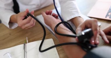 Kardiyolog doktor klinikte tonometresi olan erkek hastaya kan basıncını ölçüyor. Atardamar hipertansiyonu ve kalp sorunları teşhisi